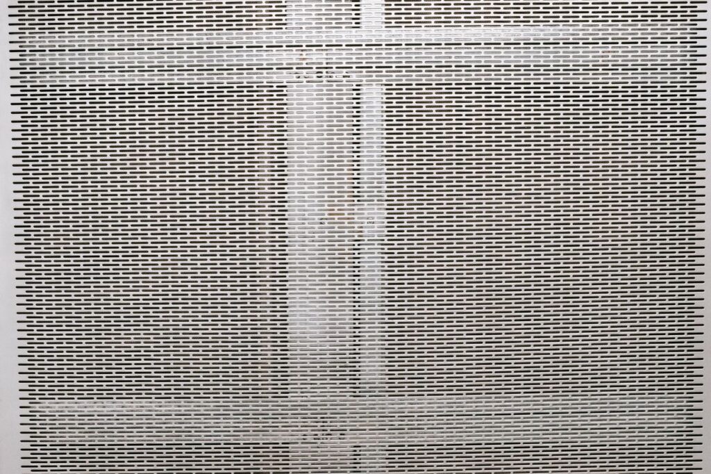 Full frame textured background of gray metal surface with geometric holes in rows